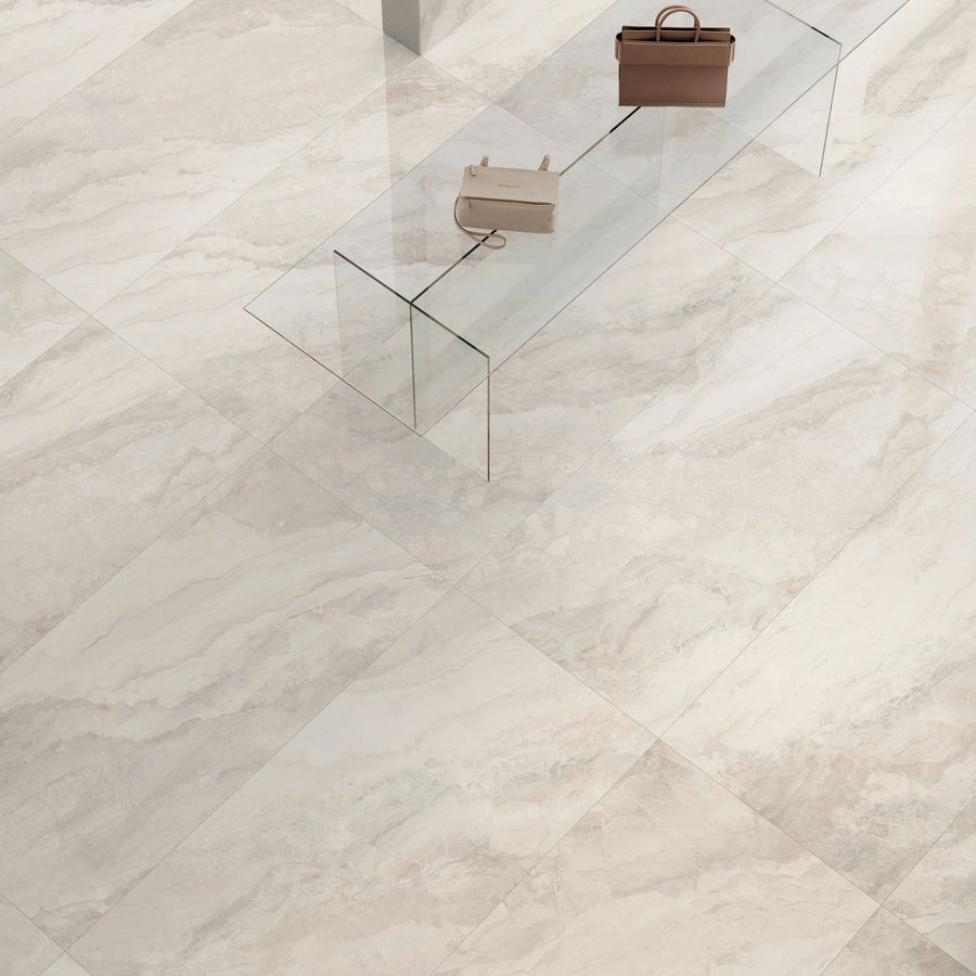 Glass coffee table with two handbags on a white marble floor